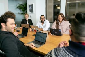 A diverse marketing team collaborating on programmatic ad buying strategy during a conference room meeting with laptops open.