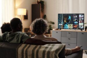 A family relaxes on the couch watching streaming content on a connected television, illustrating the ott vs ctv distinction in a home living room.