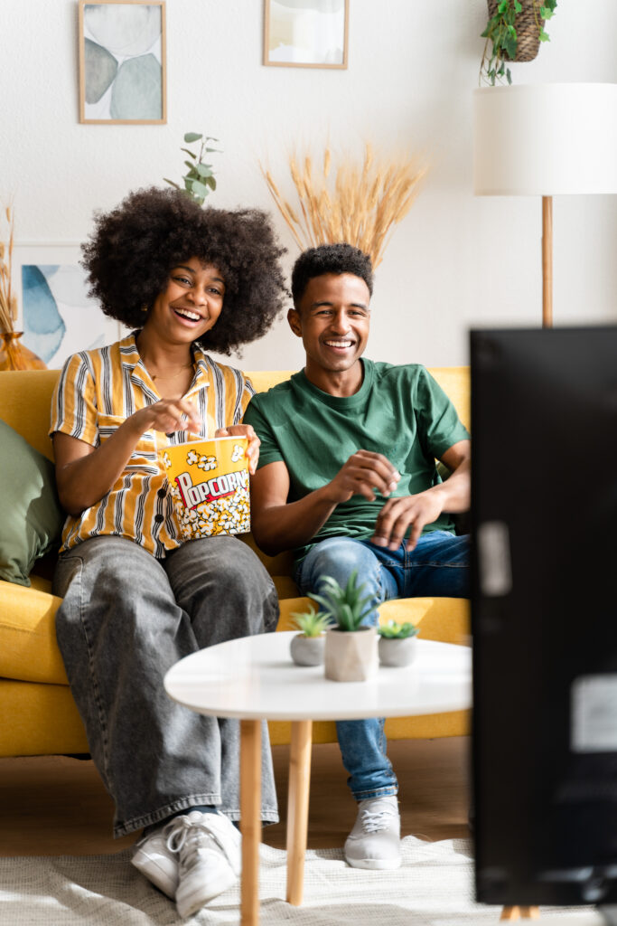 Couple watching a streaming show on a living room TV, warm evening light