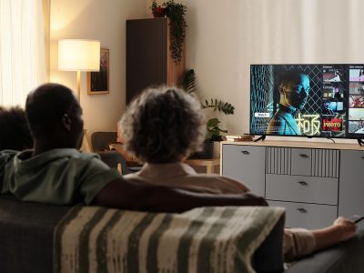 A family relaxes on the couch watching streaming content on a connected television, illustrating the ott vs ctv distinction in a home living room.